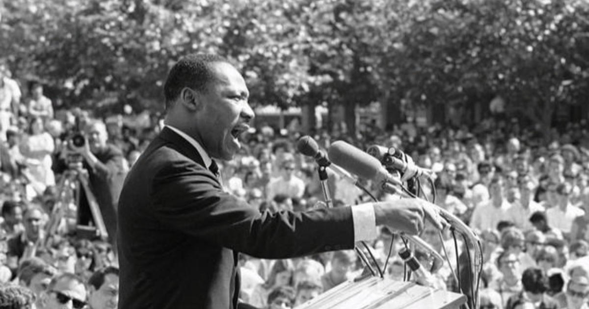 Martin Luther Kings at podium speaking to a crowd.